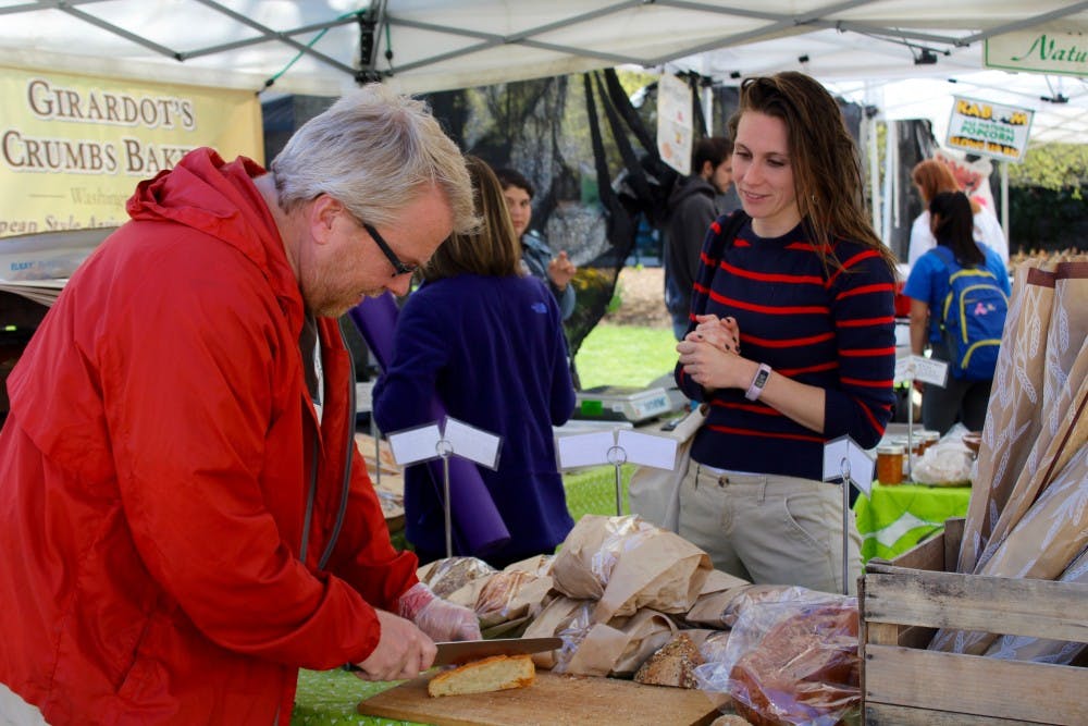 Chris Giradot sells baked goods at AU's weekly farmer's market. Patrons say they enjoy purchasing locally grown foods because it supports the livelihoods of farmers in the area.&nbsp;