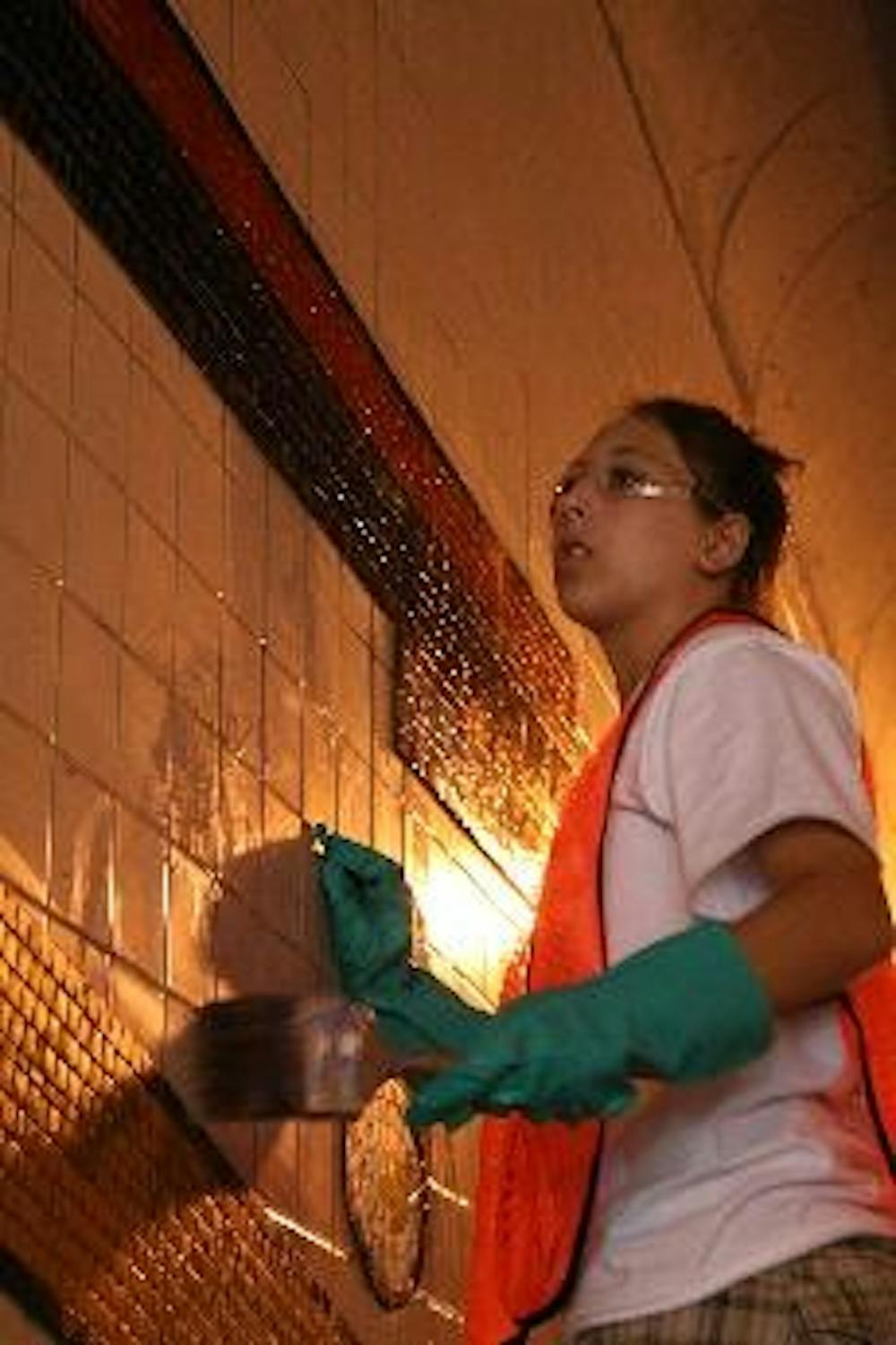 ART AS SERVICE- Freshman Celia Daly helps finish working on a mosaic mural in a 12th Street tunnel in downtown D.C. Daly and the rest of her group were working with City Arts, a nonprofit arts organization.