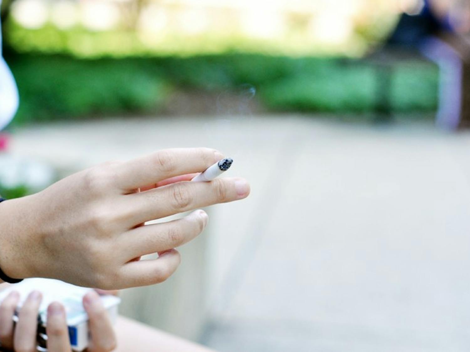 LIGHTING UP — Russel Krantz, a junior in the School of Public Affairs, takes a smoke break on the steps of the Mary Graydon Center. New signs outside of MGC and the Tavern encourage smokers to stay at least 25 feet away from the entrances of the building.