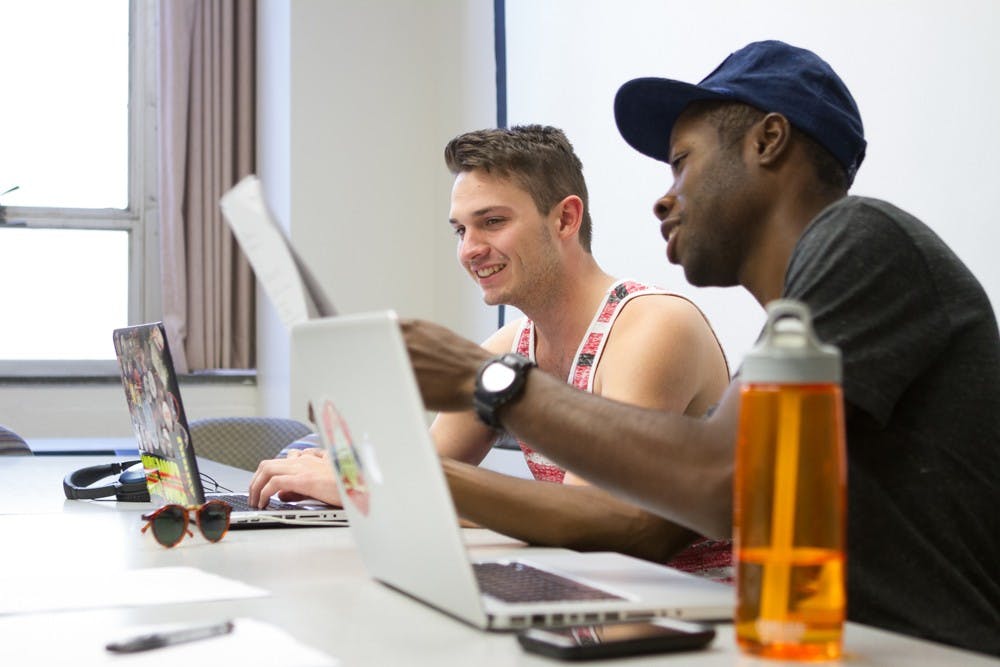 	Adrian Fernandez (left) and Devan Joseph (right) share notes while working together.