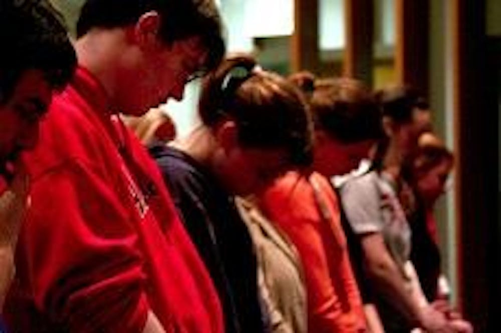 Students bow their heads in reflection and remembrance at a candlelight vigil in the Kay Spiritual Life Center Monday night. The vigil was held in honor of the 32 victims of the Virginia Tech massacre who were killed after Virginia Tech student Cho Seung-