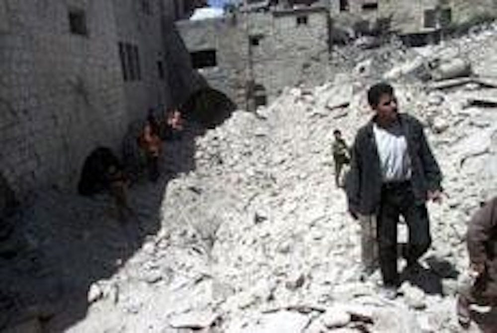 Palestinians walk over the debris of homes destroyed by Israeli missile attacks last week.