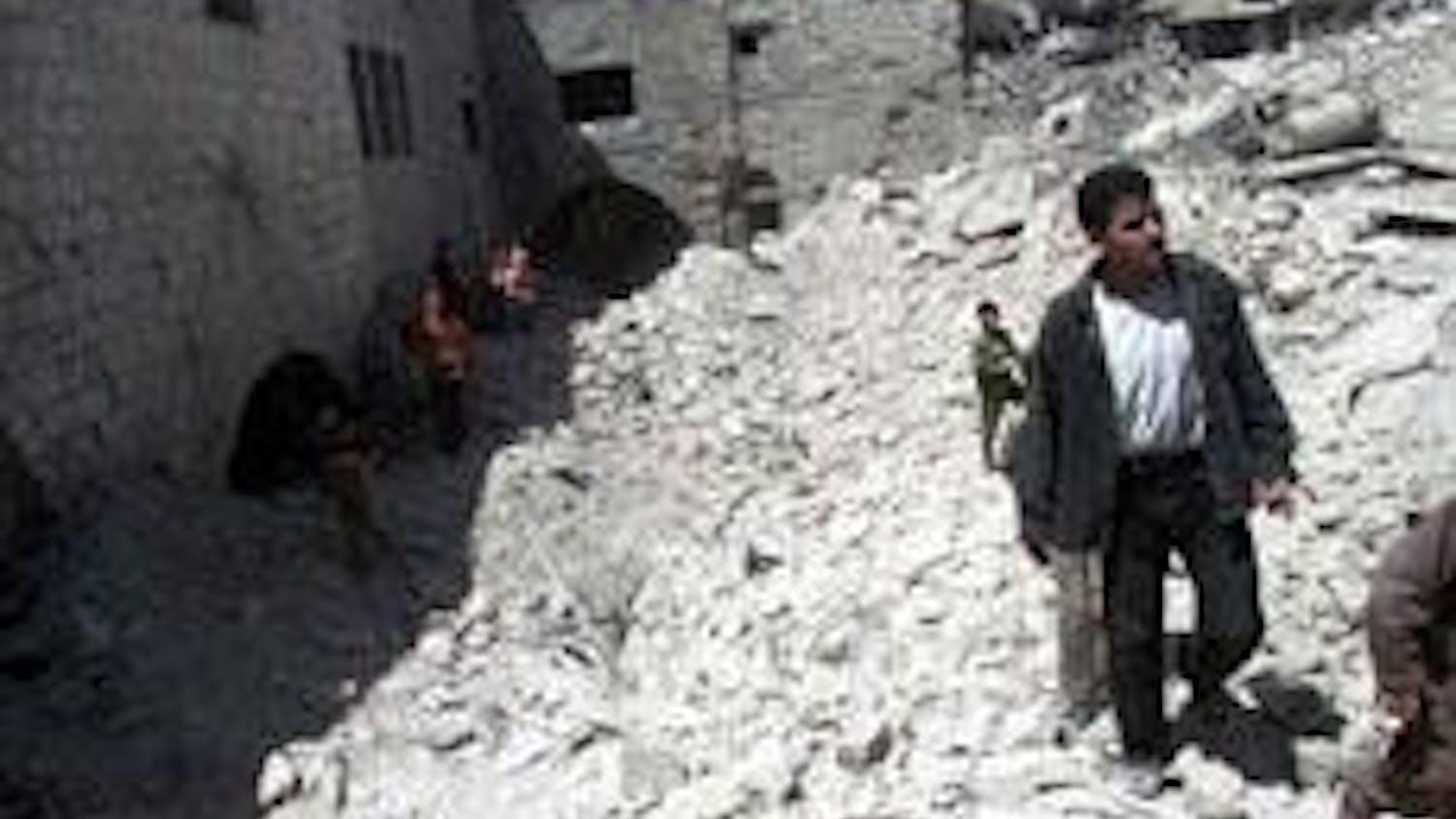 Palestinians walk over the debris of homes destroyed by Israeli missile attacks last week.