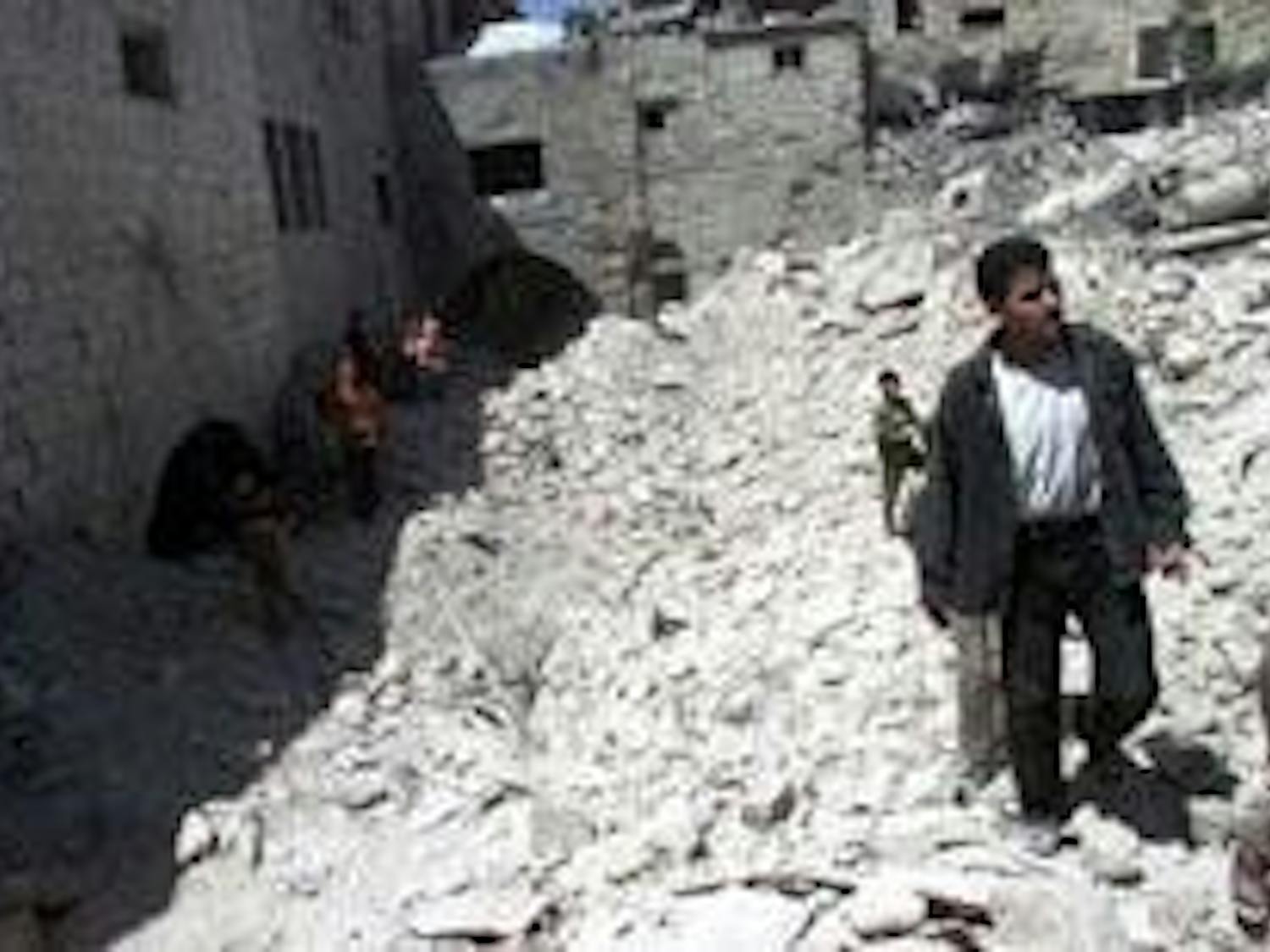 Palestinians walk over the debris of homes destroyed by Israeli missile attacks last week.