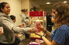 POPPIN' WITH SIGEP - Nadia Osman hands popcorn to someone attending a viewing of the movie "Wall-E" Tuesday. SigEp brothers volunteered before the screening as part of SigEp Week. The chapter will charter during a ceremony Saturday. It started as a colony