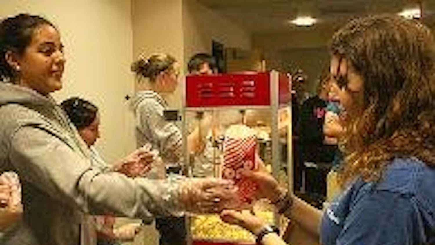 POPPIN' WITH SIGEP - Nadia Osman hands popcorn to someone attending a viewing of the movie "Wall-E" Tuesday. SigEp brothers volunteered before the screening as part of SigEp Week. The chapter will charter during a ceremony Saturday. It started as a colony