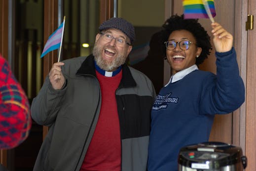 Priest and student with pride flags 