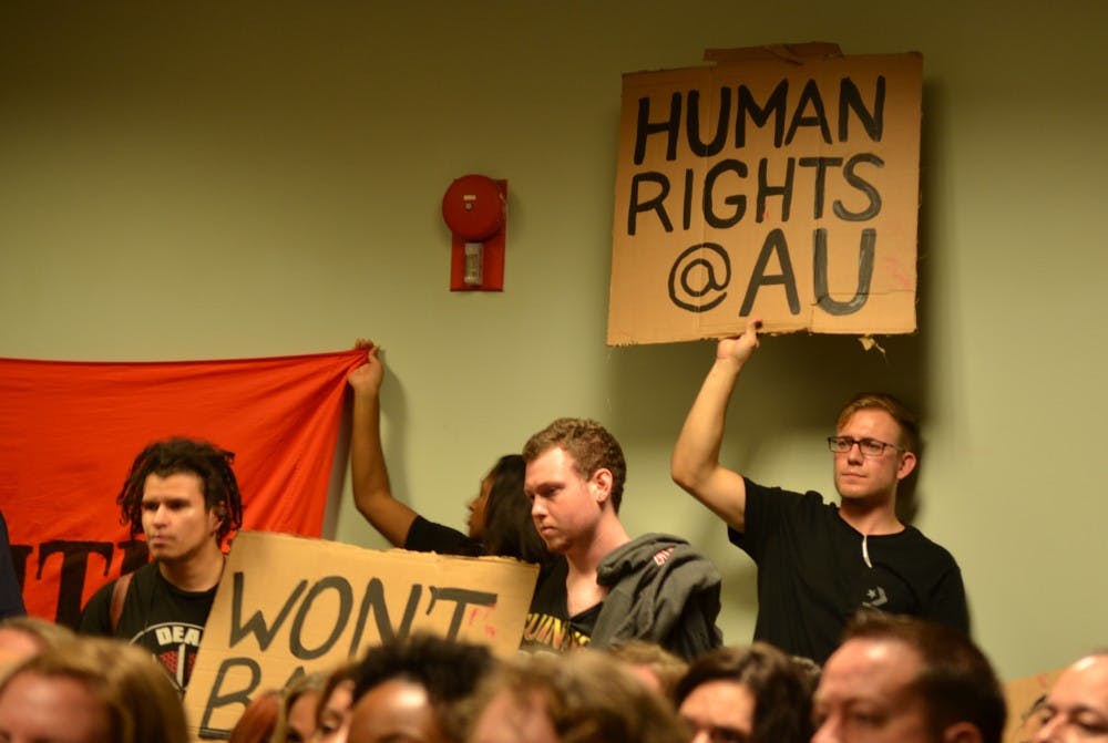 Students hold up signs&nbsp;at a town hall with President Neil Kerwin and other top University officials in late November.