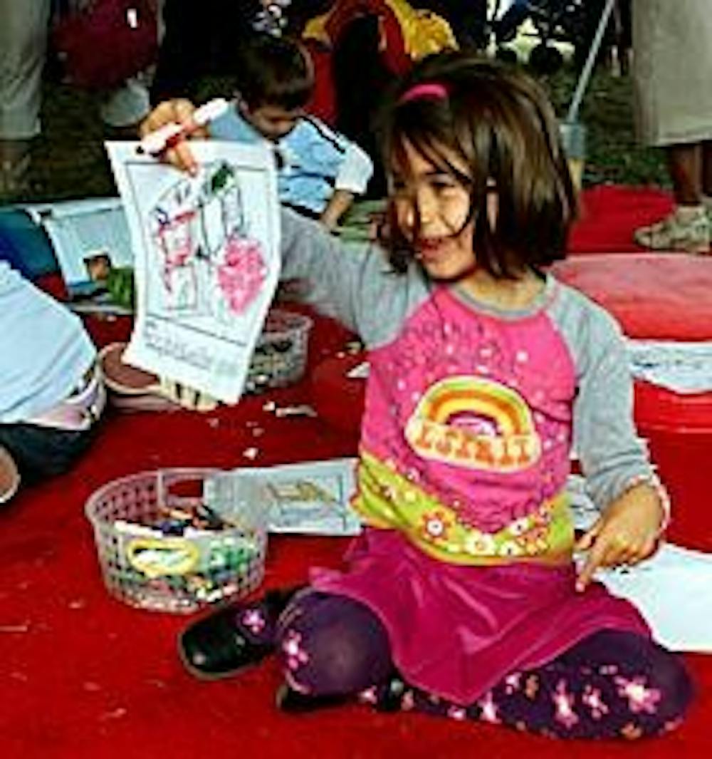 Nina McGranahan, age 5, colors a picture of the Magic Schoolbus, part of a children's exhibit. 