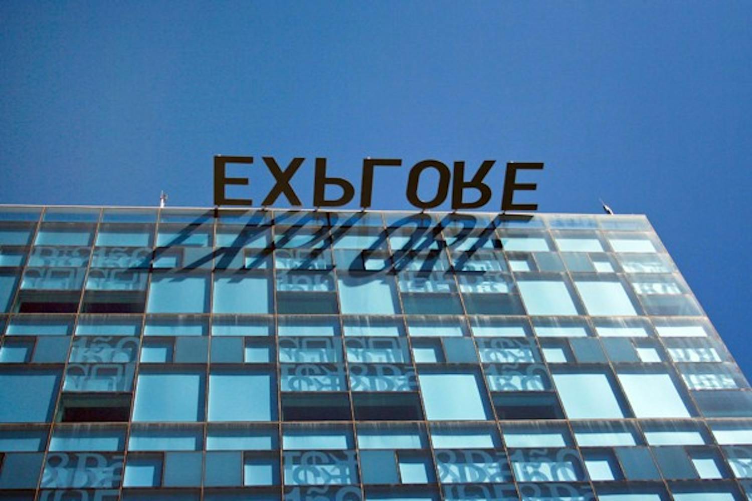 HERE COMES THE SUN: The sky is much more clear on Tuesday afternoon after Monday's rainstorm has dissappated. The sun shines bright once again and the explore sign casts a shadow on Lattie F. Coor building on the Tempe campus. (Photo by Lisa Bartoli)