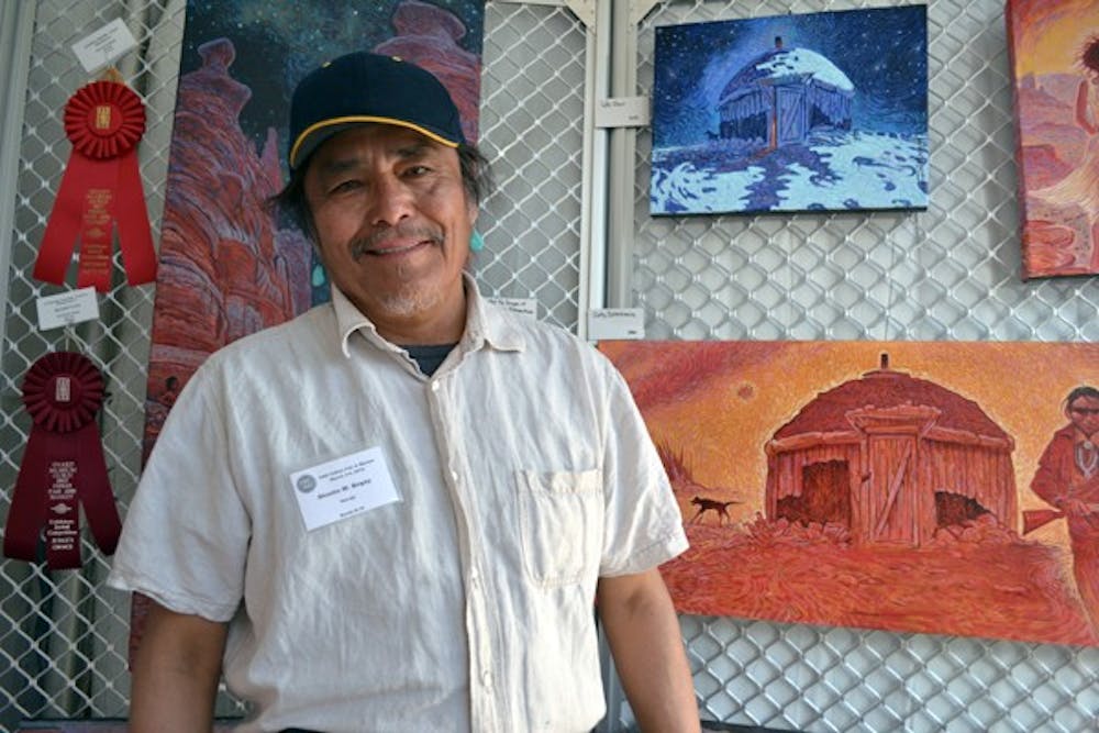 Shonto W. Begay stands proudly next to his artwork exhibited at the 54th Annual Heard Museum Guild Indian Fair and Market in downtown Phoenix. (Photo by Brittany Lea)