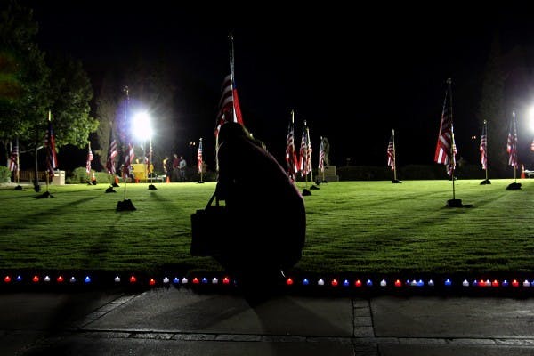Participants of the West Campus 9/11 memorial service carry red, white and blue candles through a series of flags to honor and remember those that died during the attack on the World Trade Center. This candle ceremony closed the end of the service after multiple speakers. (Photo by Tynin Fries)