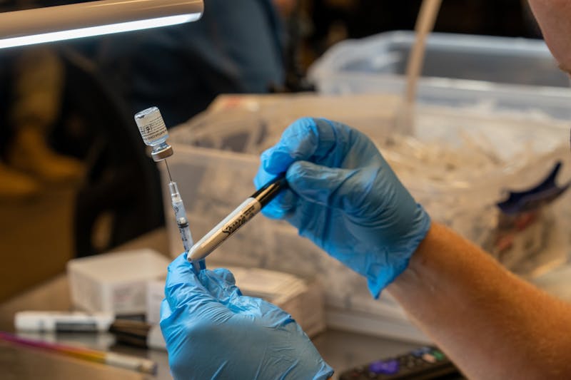 Pharmacist Trevor Lawrence fills a syringe with a dose of the Pfizer COVID-19 vaccine at Desert Financial Arena in Tempe on Wednesday, May 19, 2021.