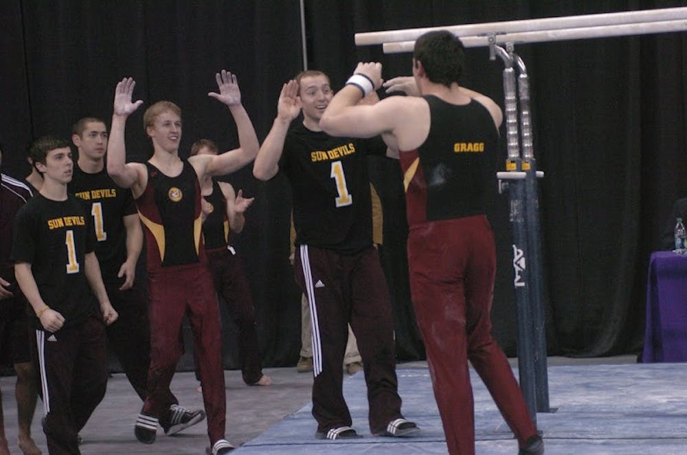 The men's gymnastics team high-fives each other. Photo courtesy of ASU Gymnastics.