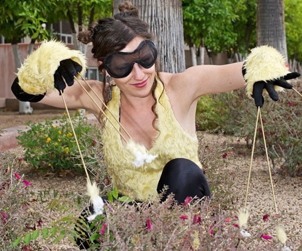 THE POLLINATRIX: Local artist Lisa Corine von Koch steps into character as the Pollinatrix, using her finger extensions to manually pollinate flowers and plant life during the Earth Week festivities on Hayden Lawn Thursday. (Photo by Michael Arellano)