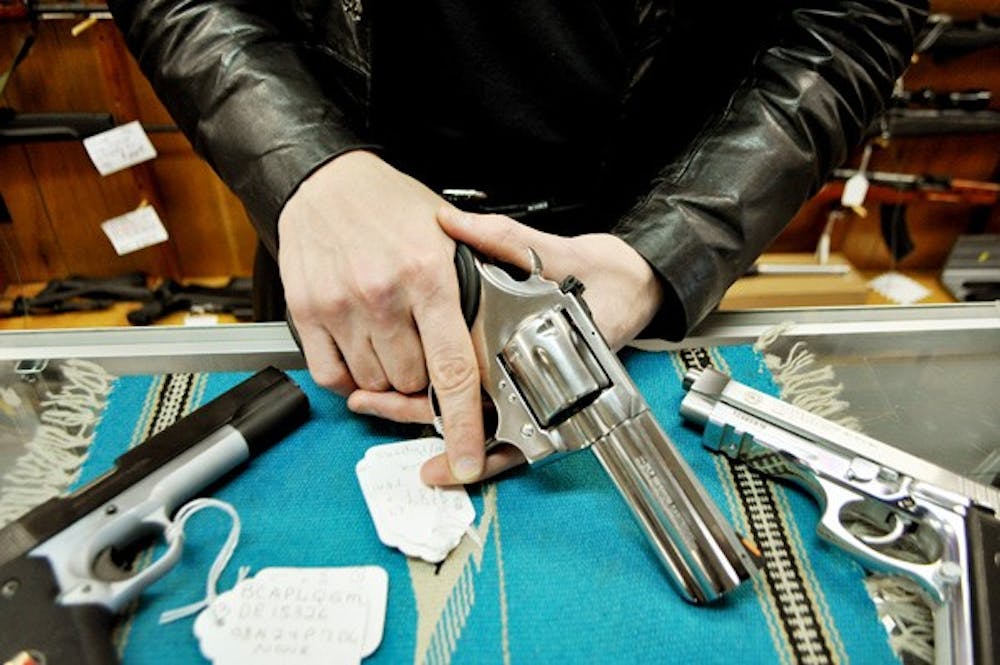 ARMED: Gun salesman Christopher Beeman handles a revolver at Arizona Firearms, Collectibles and Pawn in Tempe. Photo by Sierra Smith.