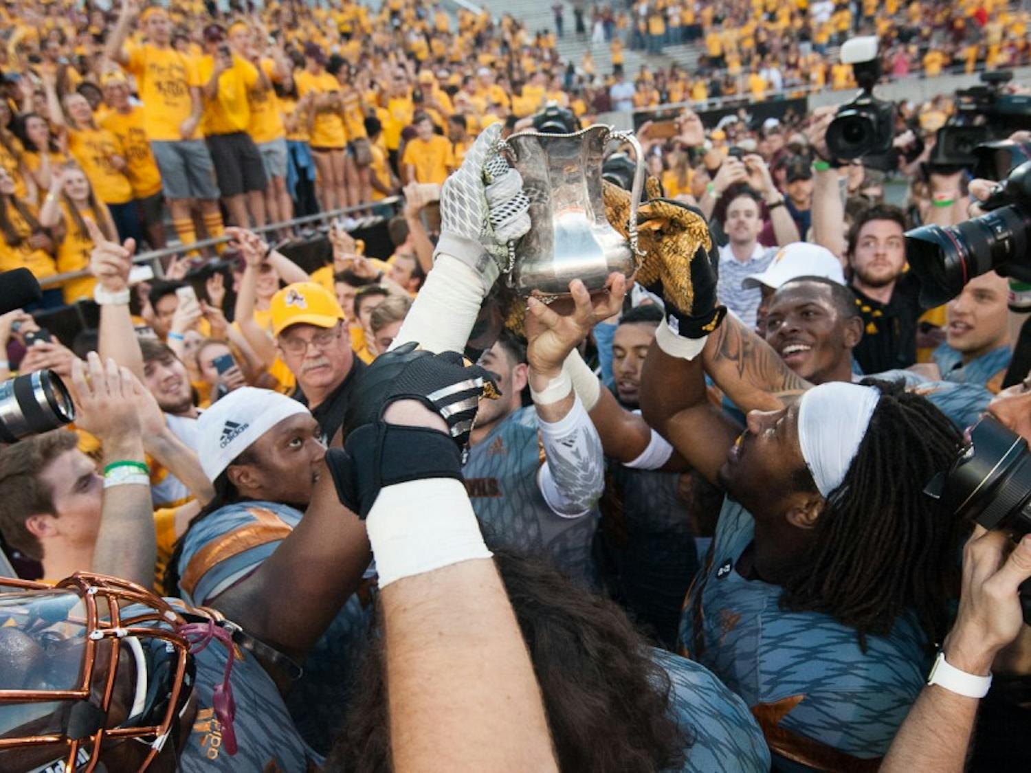 ASU football players lift the Territorial Cup in celebration after defeating UA on Saturday, Nov. 21, 2015, at Sun Devil Stadium in Tempe.