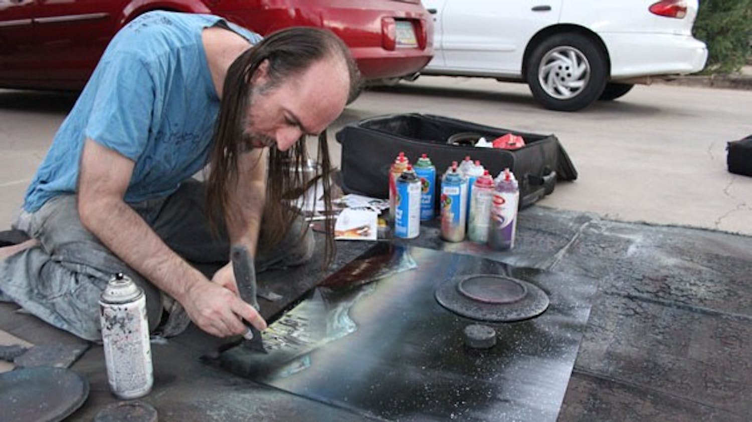 Visual artist Bruce Cormier has been painting on Mill Avenue for years. He’s a conversation-starter for frequent visitors of the street and is known for his unique style of using spray paint to create a space landscape. (Photo by Ana Ramirez)