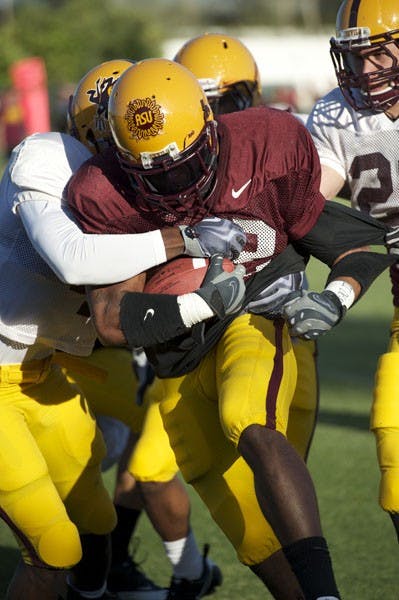 CHARGING AHEAD: ASU sophomore running back James Morrison breaks through a tackle during a spring football practice earlier this month. (Photo by Michael Arellano)