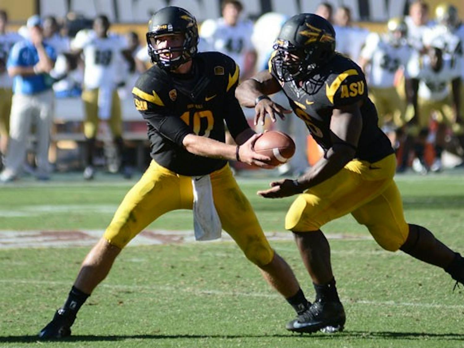 Redshirt sophomore quarterback Taylor Kelly hands the ball off to senior running back Cameron Marshall during the Sun Devils’ 45-43 loss to UCLA on Oct. 27. (Photo by Aaron Lavinsky)