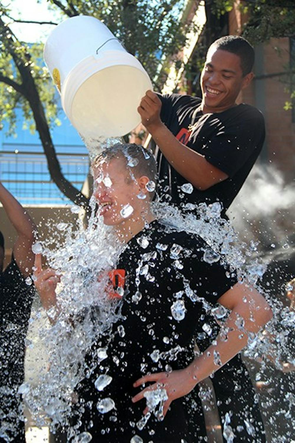 Junior Travis Stroman, along with other Ncounter employees, pours water on Tempe community members on Saturday, Aug. 23 as a part of the ALS Ice Bucket Challenge. Ncounter matched the donations that community members gave at the event. (Photo by Sawyer Hardebeck)