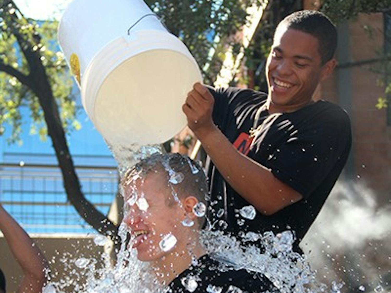 Junior Travis Stroman, along with other Ncounter employees, pours water on Tempe community members on Saturday, Aug. 23 as a part of the ALS Ice Bucket Challenge. Ncounter matched the donations that community members gave at the event. (Photo by Sawyer Hardebeck)