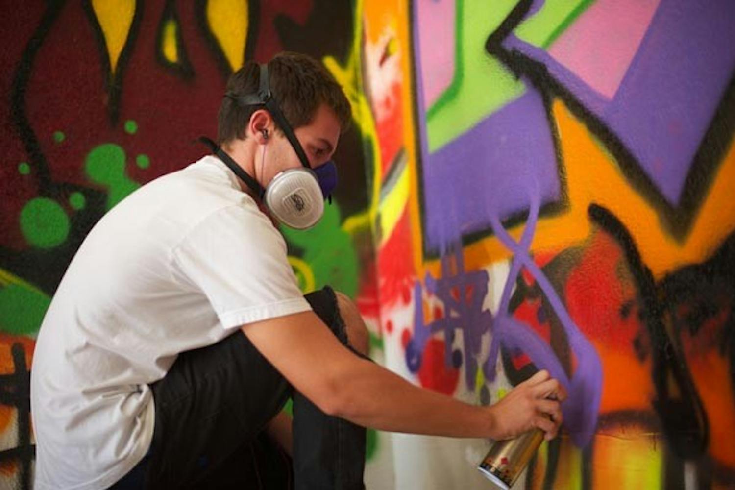 SUMMER PROJECT: Sophomore Jason Mitrione sprays a new creation onto his larger-than-life graffiti mural, covering every wall of his garage from floor to ceiling. (Photo by Michael Arellano)