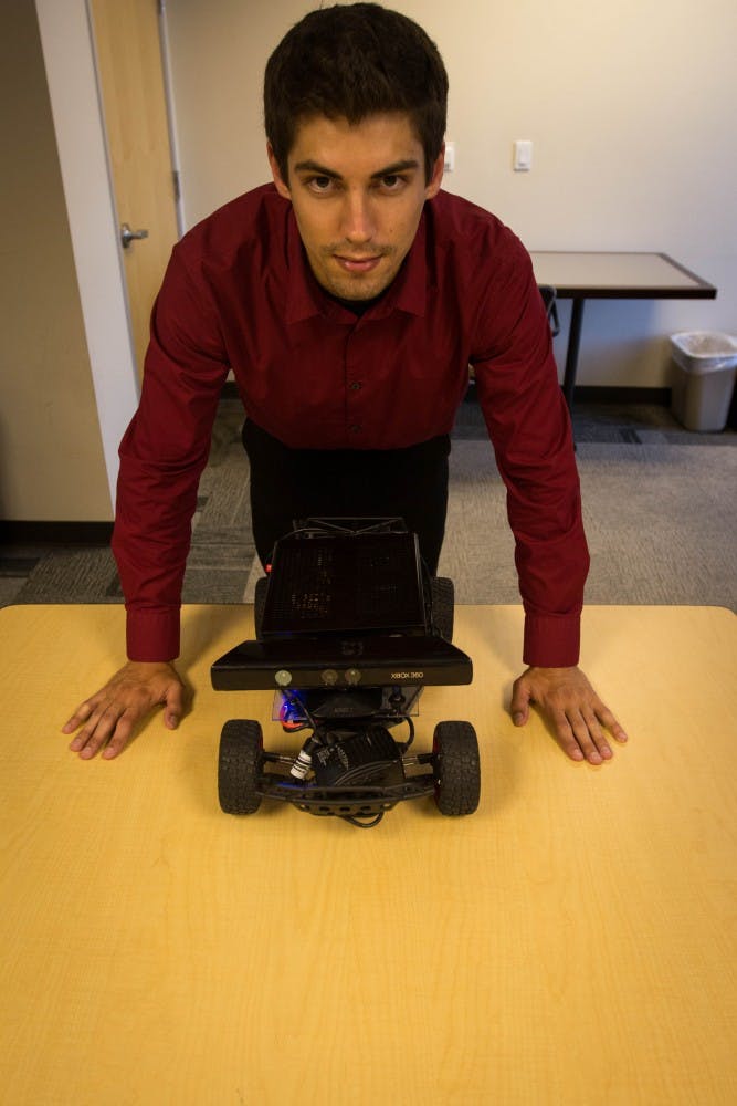 After fitting Cosmo with some final touches, Edward Andert stands over the robot in an office at the Brickyard on ASU’s Tempe Campus. Cosmo is still a prototype but will be finished “As soon as possible" according to Andert. (Photo by Dominic Valente.)