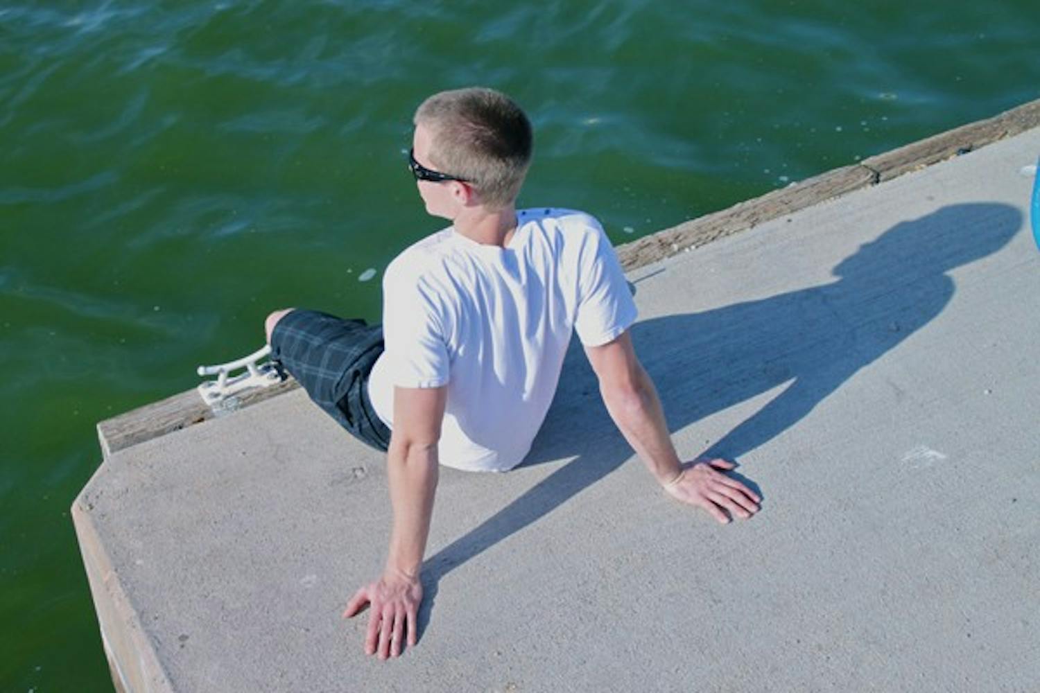 HANGING OUT: Kinesiology sophomore Matthew Cain passes the time by getting his feet wet while looking out over Tempe Town Lake after classes on Monday afternoon. (Photo by Rosie Gochnour)