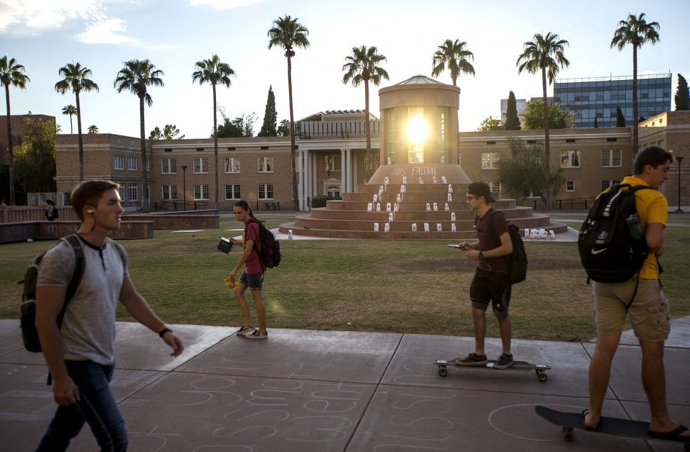 Students ride past a memorial on Hayden Lawn on the Tempe Campus on Tuesday, Sept. 27, 2016. The memorial was set up to remember the 43 students who disappeared from Ayotzinapa Rural Teachers' College in Mexico in 2014.