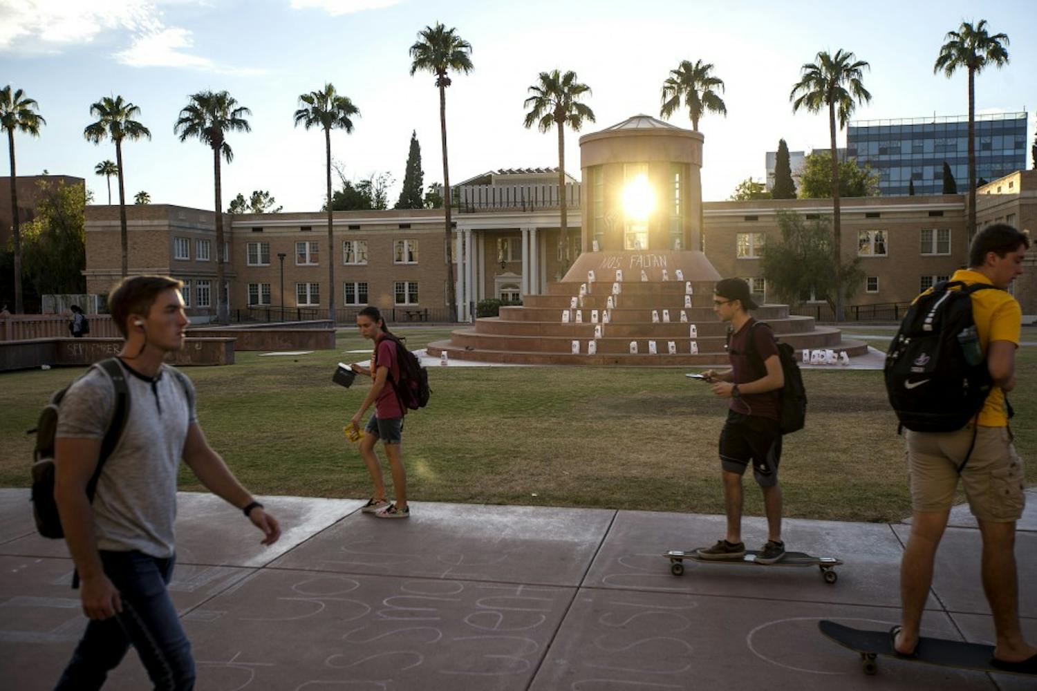 Students ride past a memorial on Hayden Lawn on the Tempe Campus on Tuesday, Sept. 27, 2016. The memorial was set up to remember the 43 students who disappeared from Ayotzinapa Rural Teachers' College in Mexico in 2014.