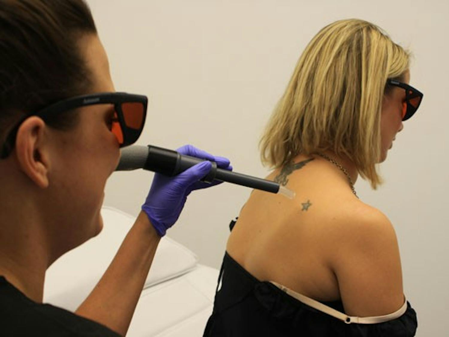 Holly Rennett, a registered nurse, begins treatment to remove a star tattoo on Tricia Corley's shoulder at Mill Avenue's Dr. TATTOFF on Nov. 15. (Photo by Jessie Wardarski)