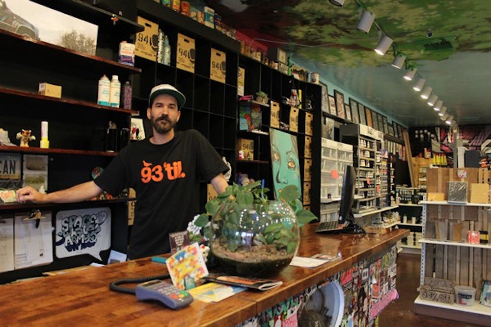 Adam Dumper, manager of Wet Paint Art Supply, stands behind the counter he has operated for 11 years. The local art supply store will close Nov. 22. (Photo by Jenn Allen)