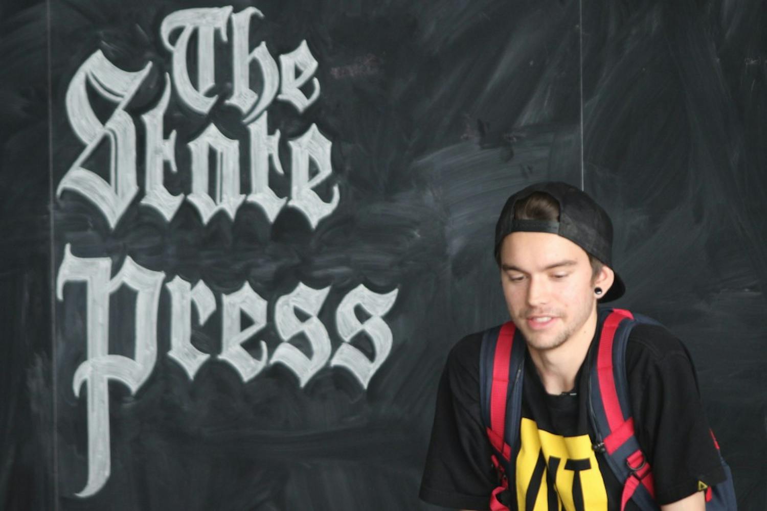 Visual communications design junior Scott Biersack sits in front of the Lattie F. Coor Hall building's chalk board, which was built in 2007. (Photo by Dominic Valente)