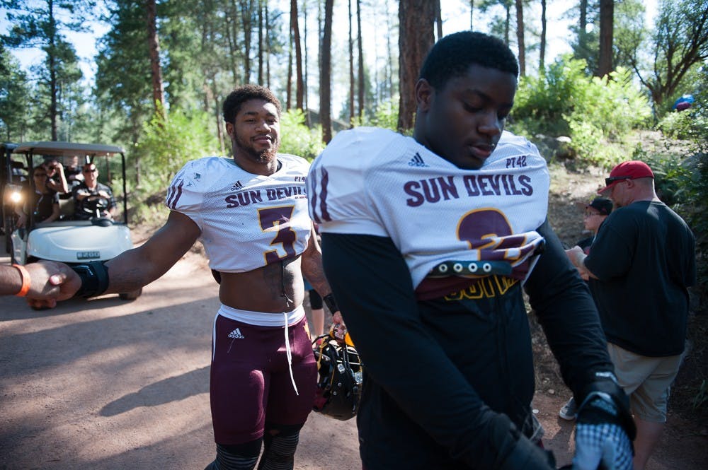 Sophomore linebacker D.J. Calhoun (left) and sophomore linebacker Christian Sam greet fans on the way to the practice field during the last day of Camp Tontozona on Saturday, Aug. 15, 2015, in Payson, Arizona.