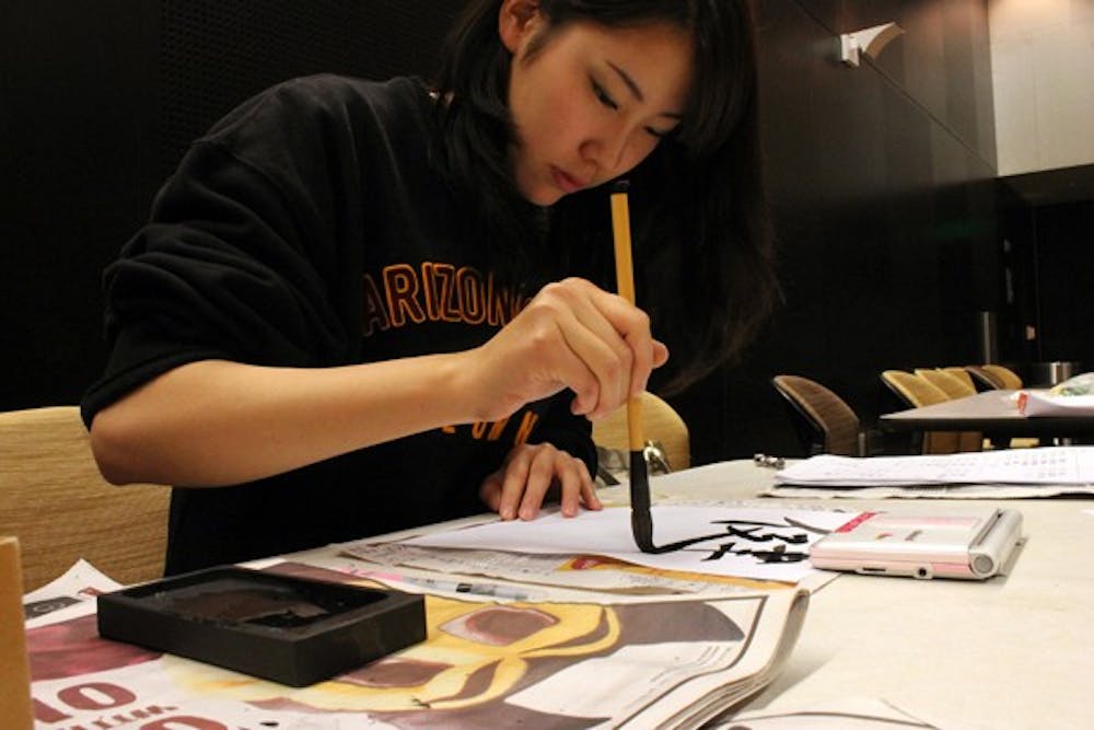 Wakana Mizutani, exchange student from Nanzan University, writes a student's name in Japanese as a part of the School of International Letters and Cultures' Annual Language Fair. The Language Fair provides high school students an opportunity to explore the languages that ASU offers. (Photo by Laura Davis)