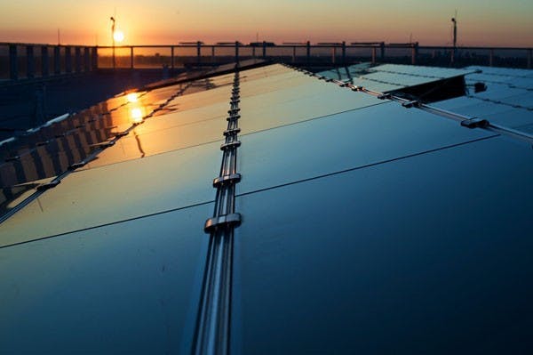 SOLAR ENERGY: The solar panel arrays atop the Coor building collect the last of the day's solar rays as the sun retreats behind the Phoenix mountains. (Photo by Michael Arellano)