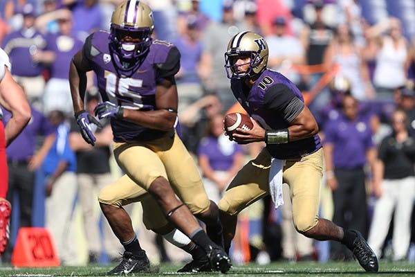 Quarterback Cyler Miles runs with the ball in a home game. (Photo by Kaia D'Albora/Photo Courtesy of The Daily of the University of Washington)