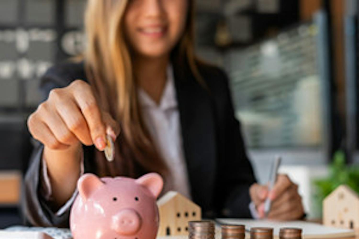 A woman puts a coin into a piggy bank. Learn the financial basics from Desert Financial Credit Union.