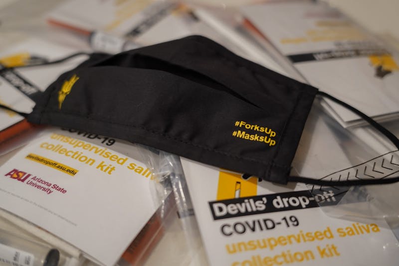 A mask from an ASU Community of Care kit sits on top of Devil's drop-off saliva testing packets.