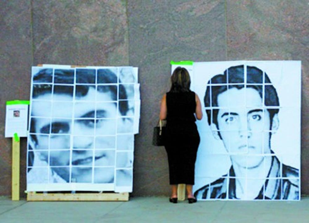 A woman stands before photos of two Iranian students on Saturday evening at the state Capitol. The students were imprisoned last year for protesting the 2009 presidential election. (Rheyanne Weaver)