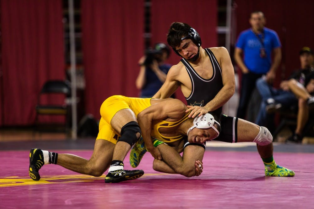 ASU junior wrestler Ares Carpio wrestles with Cal Poly freshman Yoshito Funakoshi in the 125-pound weight division match at Wells Fargo Arena on Feb. 16, 2015. The Sun Devils would win in dominating fashion beating the Mustangs 30-9. (Daniel Kwon/The State Press)