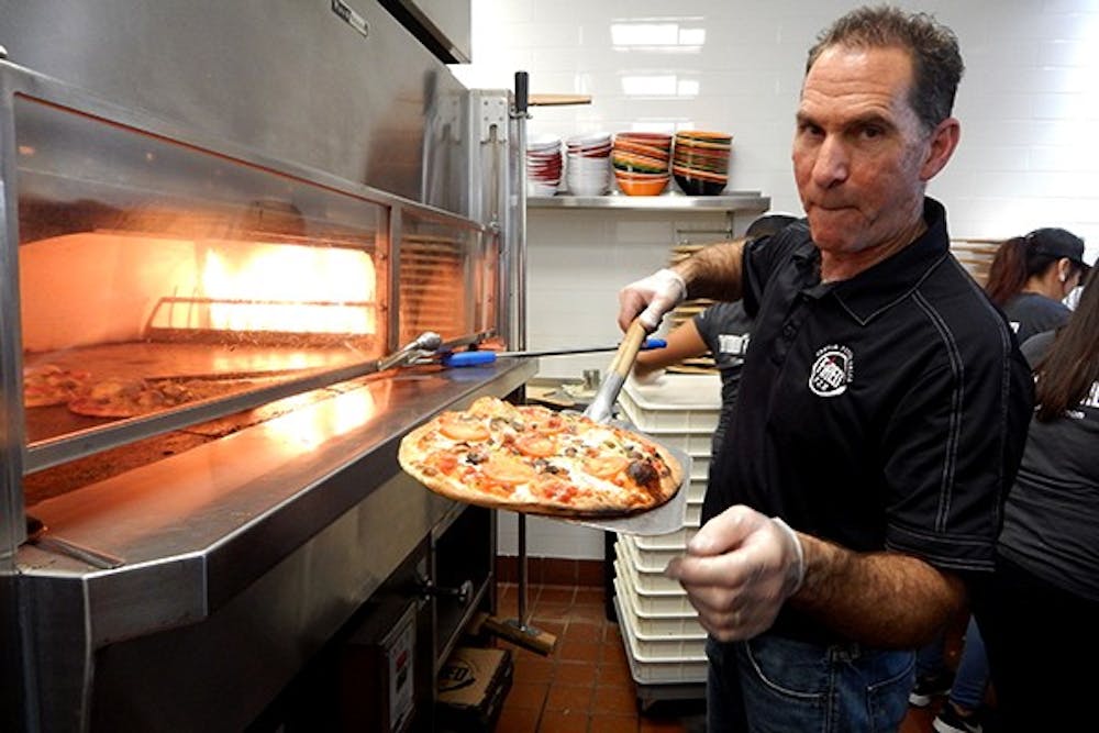 Fired Pie owner Rico Cuomo  takes a pizza out of the oven. (Photo by Olivia Richard)