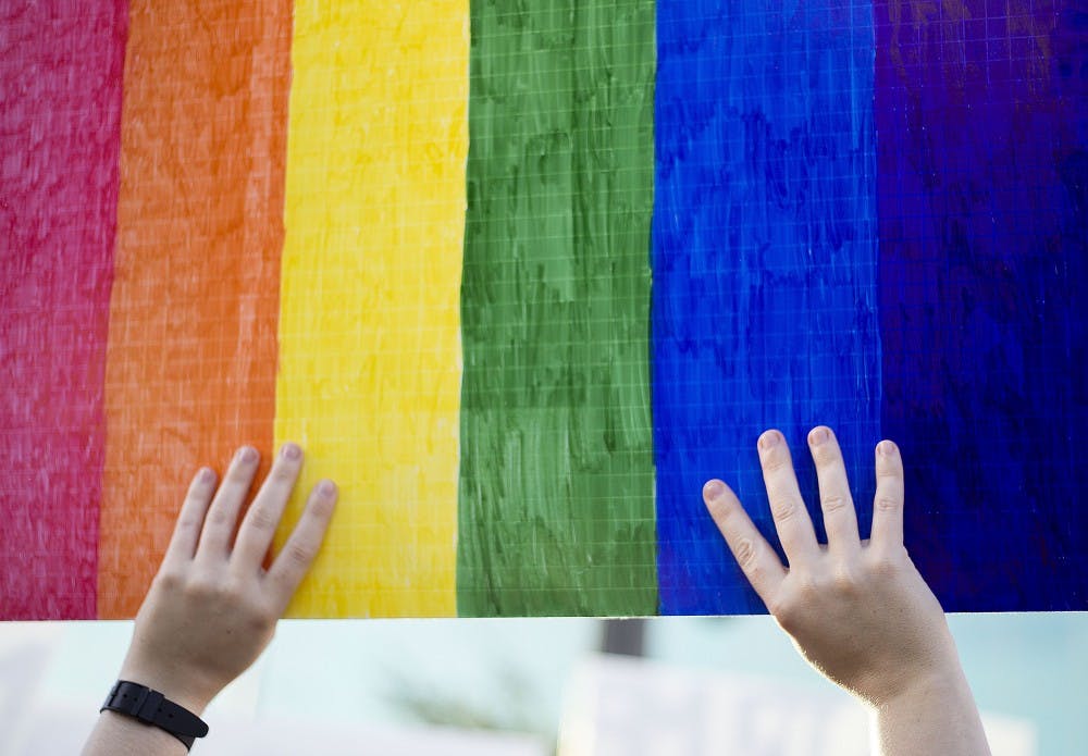 Protestors hold up signs to motorists passing by on University Drive during a protest of the 2016 presidential election results near the Old Main building on the ASU Tempe campus on Friday, Nov. 11, 2016. 