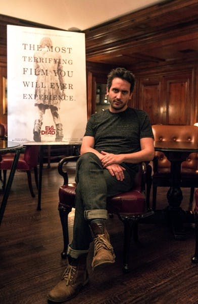 Fede Alvarez sits next to his Evil Dead poster at the Ritz Carlton in Phoenix. The movie is scheduled to come out in early April of this year. (Photo by Dominic Valente)