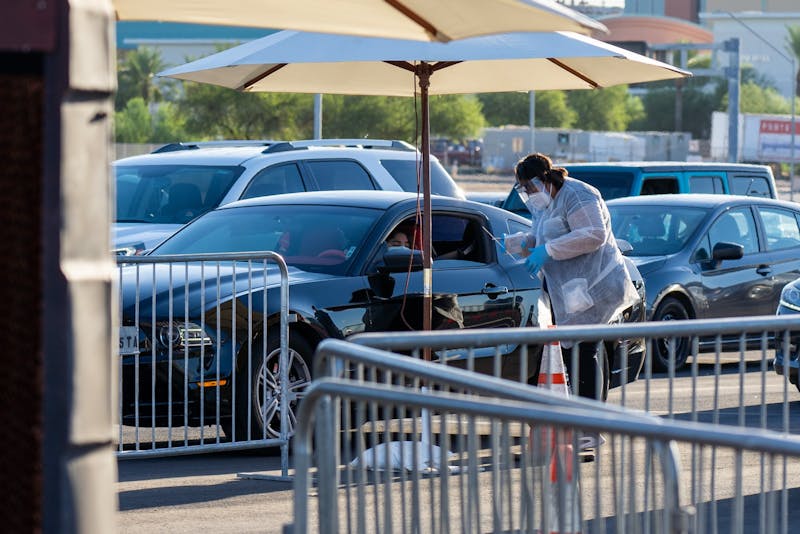 A volunteer explains the saliva testing process to a recipient of the test on Tuesday, July 28, 2020, outside State Farm Stadium in Glendale.&nbsp;