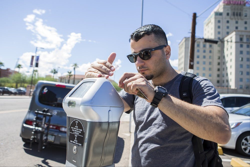 ASU student Tsahai Dias pays for a parking spot on Filmore Street across from the Walter Cronkite School of Journalism and Mass Communication in downtown Phoenix on Sept. 15, 2015. Dias said his downtown classes have forced him to park in metered spots this semester due to a lack of additional parking options. 