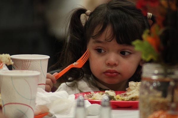 HELPING KIDS: A young girl enjoys a Thanksgiving dinner that a group of Mormon ASU students helped provide and serve at a local Boys and Girls Club for children and their families. They served over 200 meals. (Photo by Rosie Gochnour)