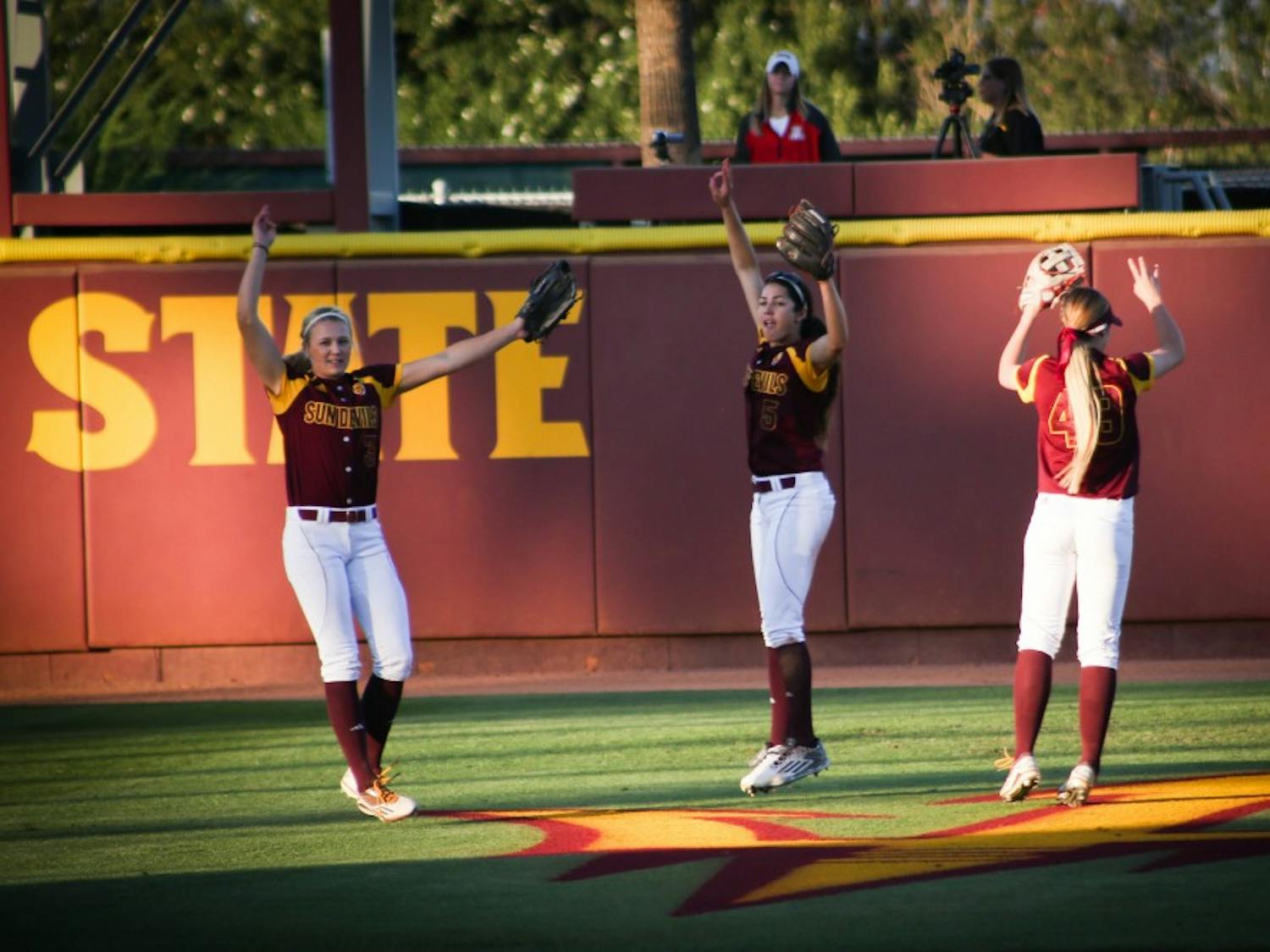 Senior Abby Spiel (#3), Senior Jennifer Soria (#5), and Sophomore Nichole Chilson (#49) huddle together in the outfield and then explode out in team spirit at the ASU vs Arizona softball game on March 18, 2016.
