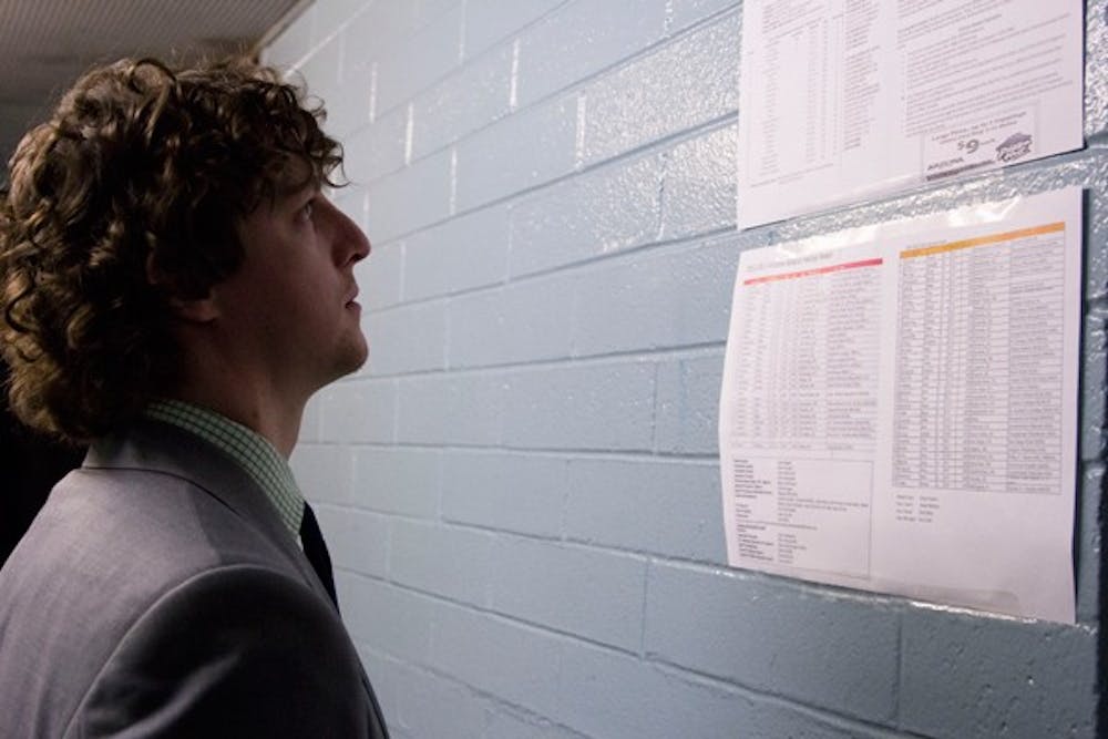 Assistant coach Blossey stares at the roster for both UA and ASU teams.  (Photo by Ana Ramirez)